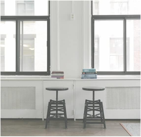 two stools facing two windows with two stacks of text books